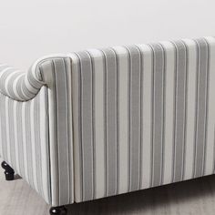 a striped couch sitting on top of a hard wood floor next to a white wall