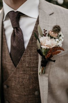 a man wearing a suit and tie holding a boutonniere with flowers on it