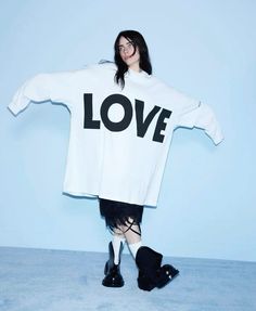 a woman in black boots is holding a white shirt with the word love on it