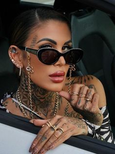 a woman with tattoos and piercings sitting in a car looking out the window at something