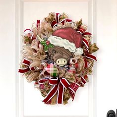 a christmas wreath with a cow wearing a santa hat on it's front door