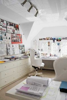 an office with white furniture and lots of papers on the desk