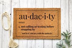 a door mat with the words audacty on it next to a plant