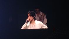 a man holding a microphone up to his ear while standing in front of a stage