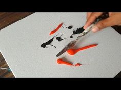 someone is using scissors to paint an image on canvas with black and orange inks