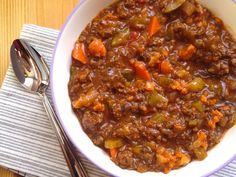 a bowl of chili with carrots and green peppers