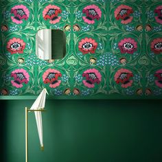 a green room with pink flowers on the wall and a mirror in the corner next to it