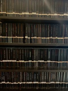 several rows of black books on shelves in a library with white and red labels attached to them