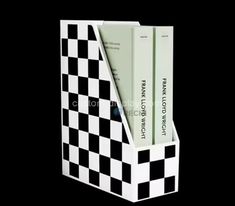 a black and white checkerboard book holder with two books in the bottom section