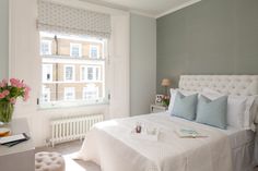 a white bed sitting in a bedroom next to a window with pink flowers on it