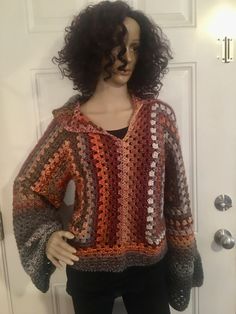 a mannequin is standing in front of a door wearing a crocheted sweater