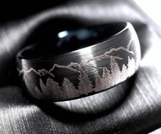 a wedding band with mountains and trees engraved on it