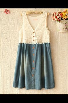 a white and blue dress hanging on a wall next to a potted plant with flowers