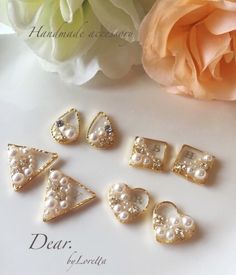 five pieces of pearl and gold jewelry sitting on top of a white table next to a flower