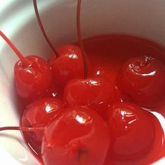 a white bowl filled with cherries sitting on top of a table