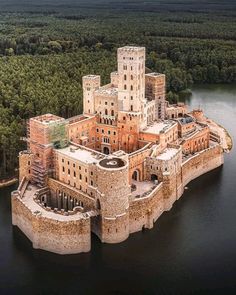 an aerial view of a castle in the middle of a body of water with trees surrounding it