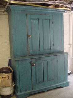 an old blue cabinet sitting in a room next to a bucket and some other items