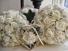 a heart shaped basket sitting on top of a table next to white flowers