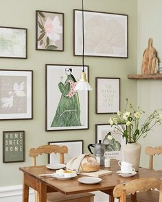 a dining room table with chairs and pictures on the wall above it, along with other decor items