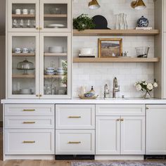 a kitchen with white cabinets and gold pulls on the cupboards, along with an area rug