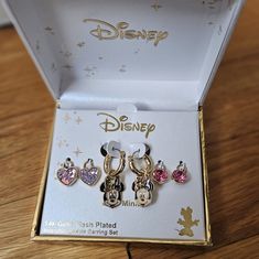 three pairs of disney mickey mouse earring sets in a box on a wooden table