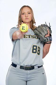 a female baseball player holding a ball and glove