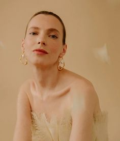 a woman in a white dress with large gold earrings