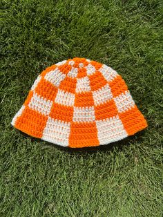 Elevate your style with our vibrant, Orange and White Crochet Checkered Bucket Hat! handcrafted with care and attention to detail, this unique accessory is perfect for adding a pop color in a touch of warmth to your outfits, making it ideal for game day excitement and beyond. Key Features: Eye-Catching Design: Our crocheted checkered pattern combines bold orange and crisp white to create a visually striking design that should turn heads.  Versatile Fashion: Whether you're heading to a game day, White Yarn Festival Hat, Orange Adjustable Beanie Hat, Adjustable Orange Beanie Hat, Handmade Casual Orange Crochet Hat, Orange Crochet Outfit, Adjustable Orange Beanie, Handmade Orange Hat For Vacation, Handmade Orange Crochet Hat For Beach, Orange Crochet Hat, One Size Fits Most