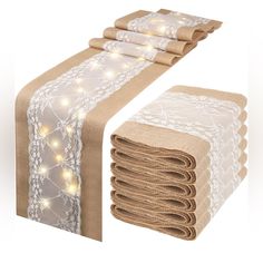 a table runner with white lace and lights on it next to a stack of napkins