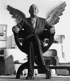 a man sitting in a chair with wings on the back of his head and legs