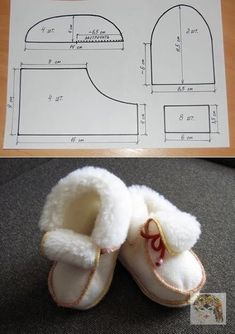 a pair of baby shoes sitting on top of a table next to a paper pattern