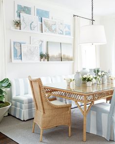 a dining room table with chairs and pictures on the wall above it, along with potted plants