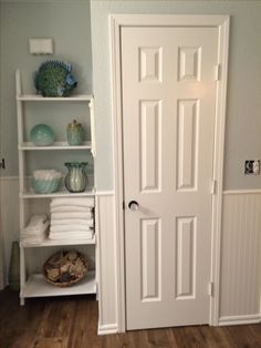 there is a white door and shelves in this room with towels on the shelfs