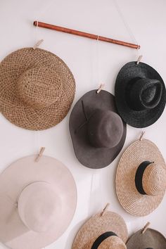 several hats hanging on a wall with clothes pins