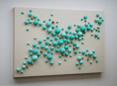 an abstract painting with blue and gold balls on it's side, hanging on the wall