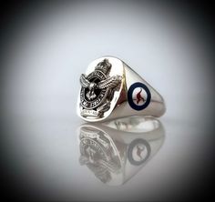 Royal Australian Air Force Ring  This ring has RAAF emblem on sides in traditional colors of which has been laser etched into sides with enamel color   This ring has been hand made in our studio by our own skilled silversmith Artisans it is solid back filled for a comfort fit.  Measurements are 20mm high by 18mm wide on face of ring and is all sterling Silver 92.5 percent.   The emblem has been Oxidized which is darkened silver but is on a highly polished background you also have the choice to c Hiram Abiff, Royal Australian Air Force, Masonic Ring, Military Fashion, Real Gold, Signet Ring, Silver Band, Makers Mark, Class Ring