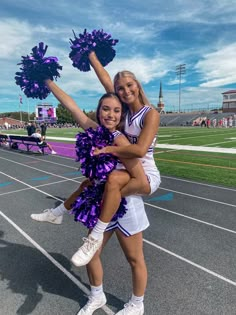 two cheerleaders are posing on the sidelines