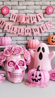 a table topped with halloween decorations and pink skulls on top of eachother's head