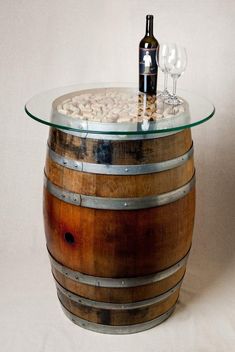 a wine glass and bottle on top of a wooden barrel with rocks in the bottom