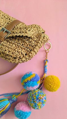 two pom poms and a purse on a pink surface