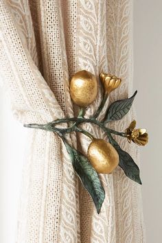 a curtain with gold flowers and leaves on it's side hanging from a rod