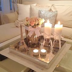 candles are lit on a tray in front of a couch with white pillows and throw pillows