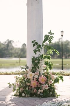 a cross with flowers and greenery on the ground