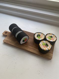 four sushi rolls on a cutting board next to a window