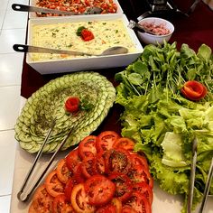 several different types of food sitting on a table with utensils and salads