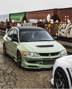 two cars parked next to each other in front of train tracks