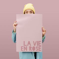 a woman holding up a sign with the words la vie en rose written on it