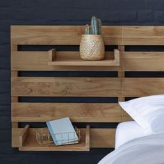 a bed with two wooden shelves on the wall above it and a plant in a vase