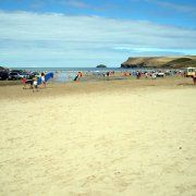 people are walking on the beach with cars parked in the sand and water behind them