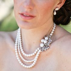 a woman wearing a necklace with pearls on it